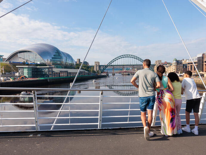 Familia de pie en un puente con vistas al río de la ciudad