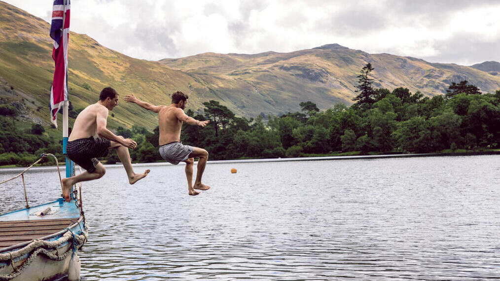 Two men jumping off a boat into the lake