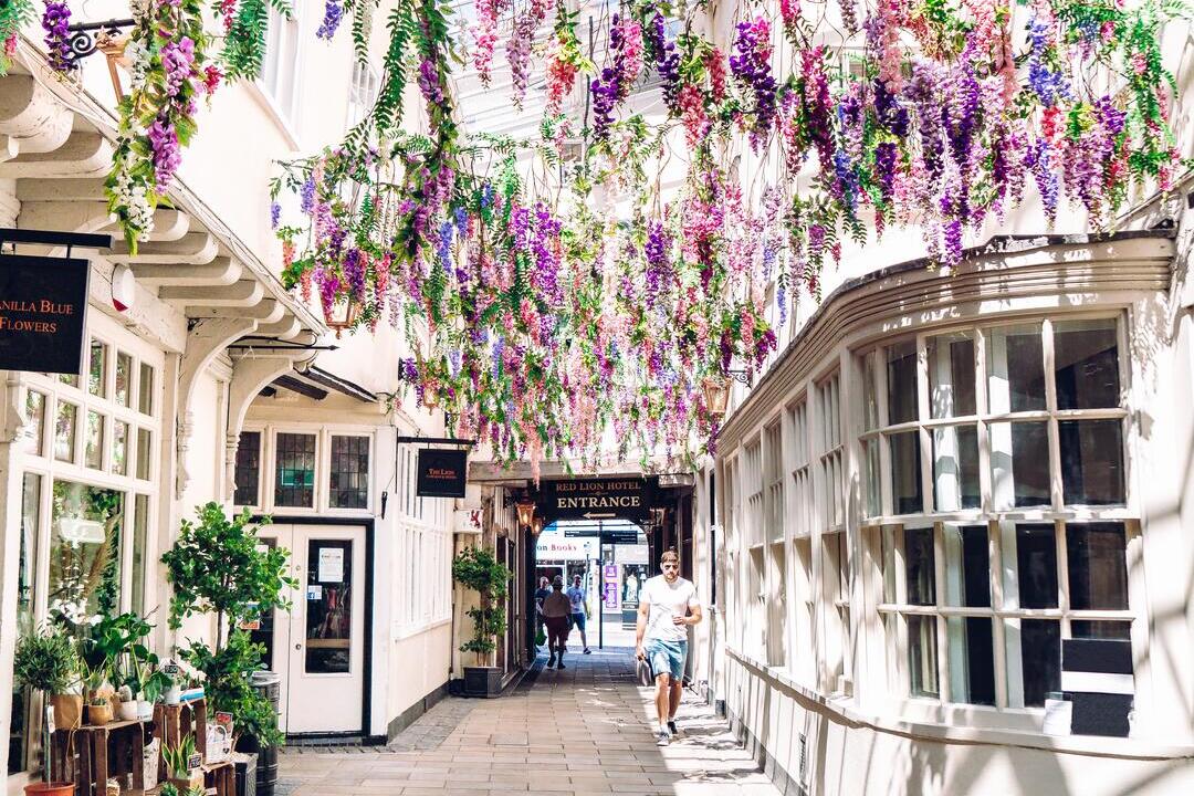Mann, der durch einen mit Blumen bedeckten Bogen im Lion Walk in Colchester geht