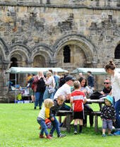 Groups of people eating and shopping outside Kirkstall Abbey