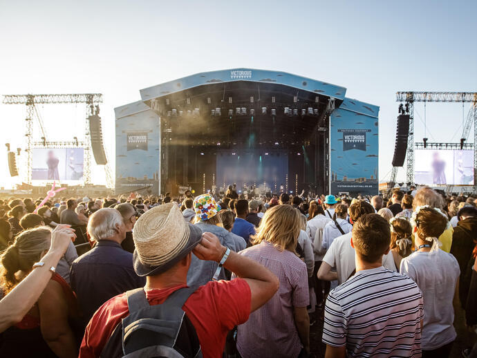 A large crowd enjoying a band on stage at an outdoor concert.