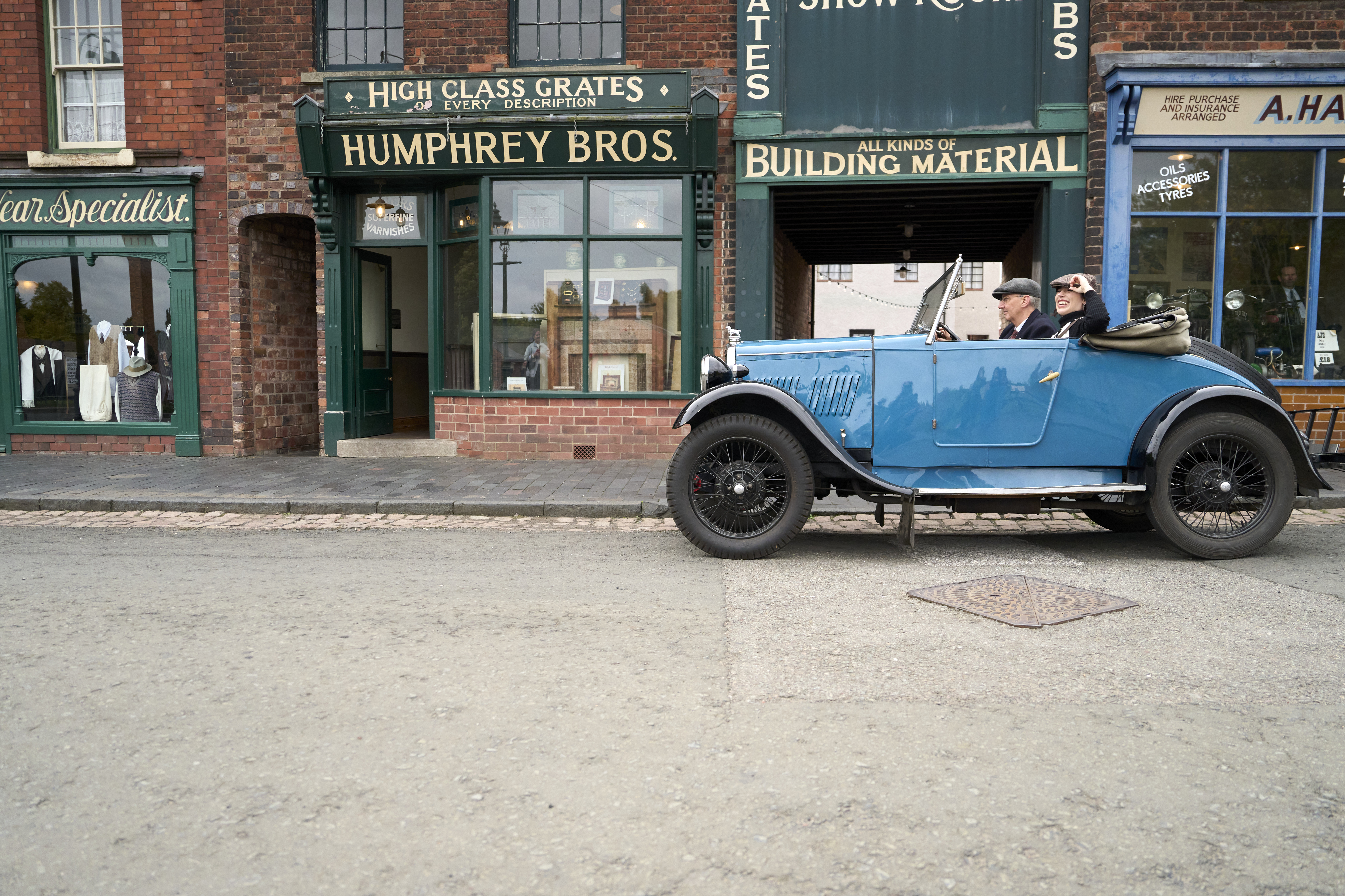Two people inside a vintage car at a living museum