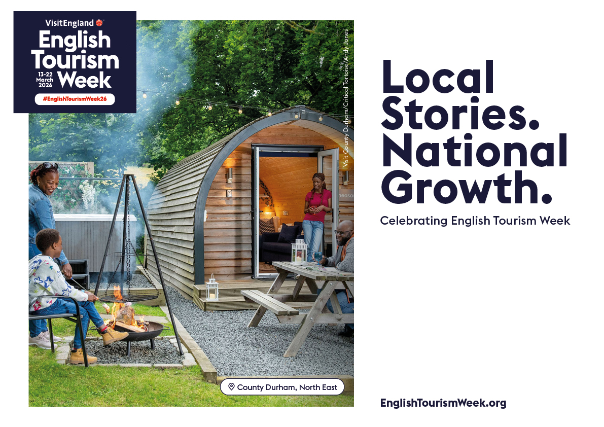 People enjoy a campfire and picnic outside a wooden cabin surrounded by trees, promoting English Tourism Week in County Durham, North East.