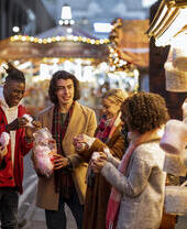 Groupe de jeunes amis partageant un sac de barbe à papa au marché de Noël.