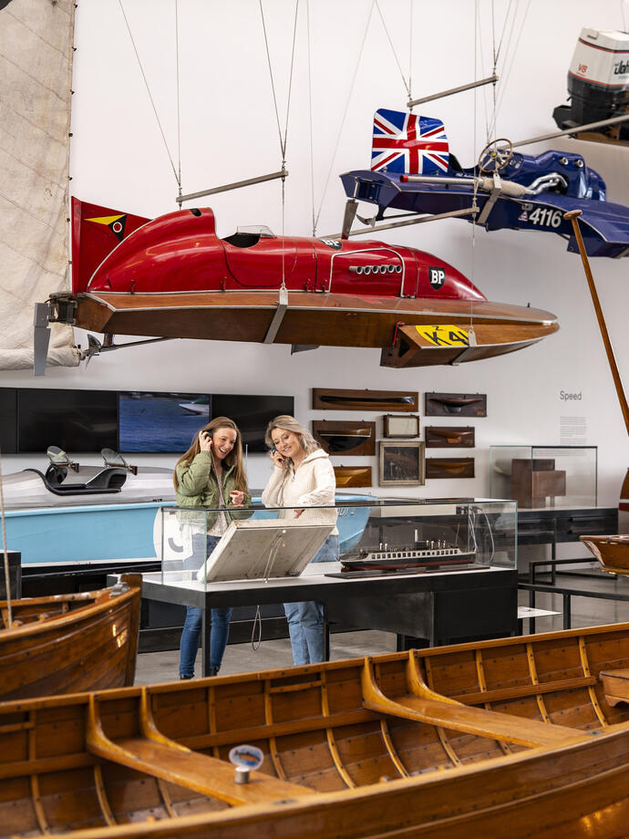 Two women listen to an audio commentary in a museum