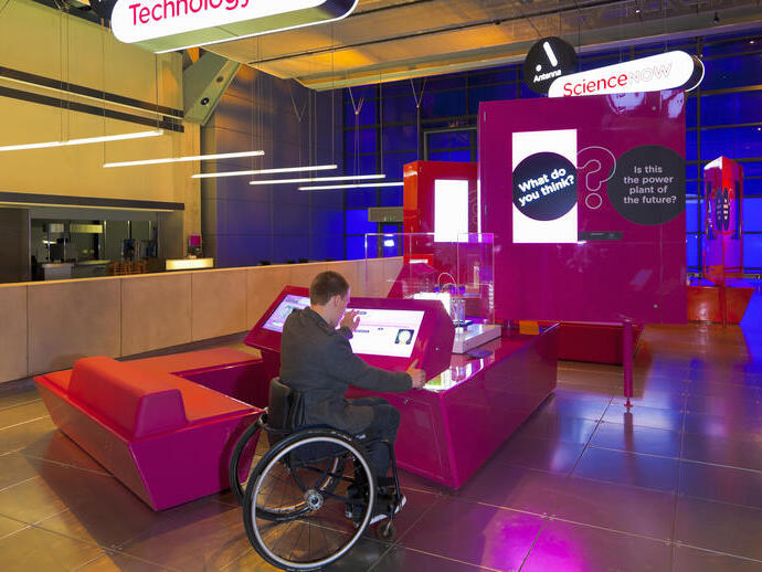 Man in a wheelchair using an interactive display in a museum