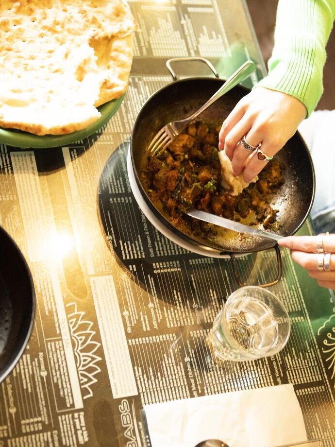 A curry dish and naan bread on the side served at a restaurant