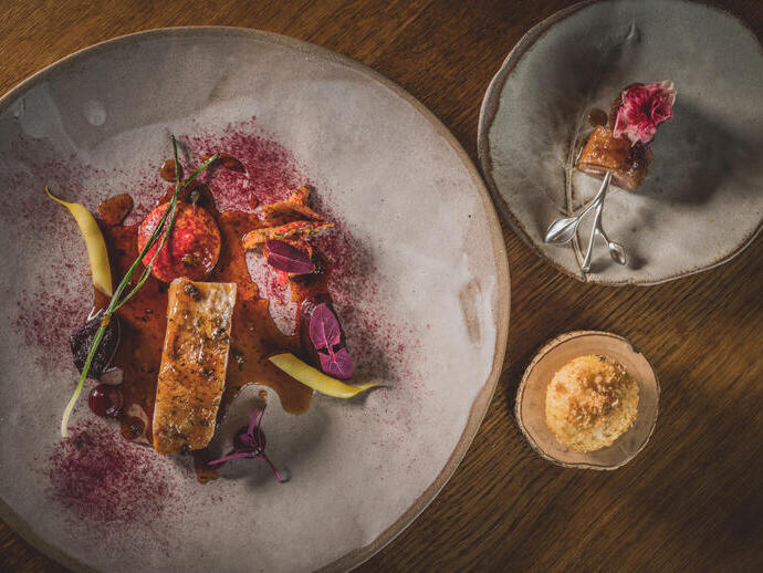 Three different sized plates of colourful food served on rustic grey crockery