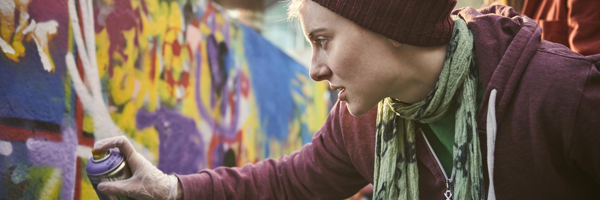 Woman using a can of spray paint to create a street art mural