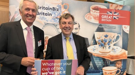 Nick De Bois posing in front of VisitBritain promotional materials