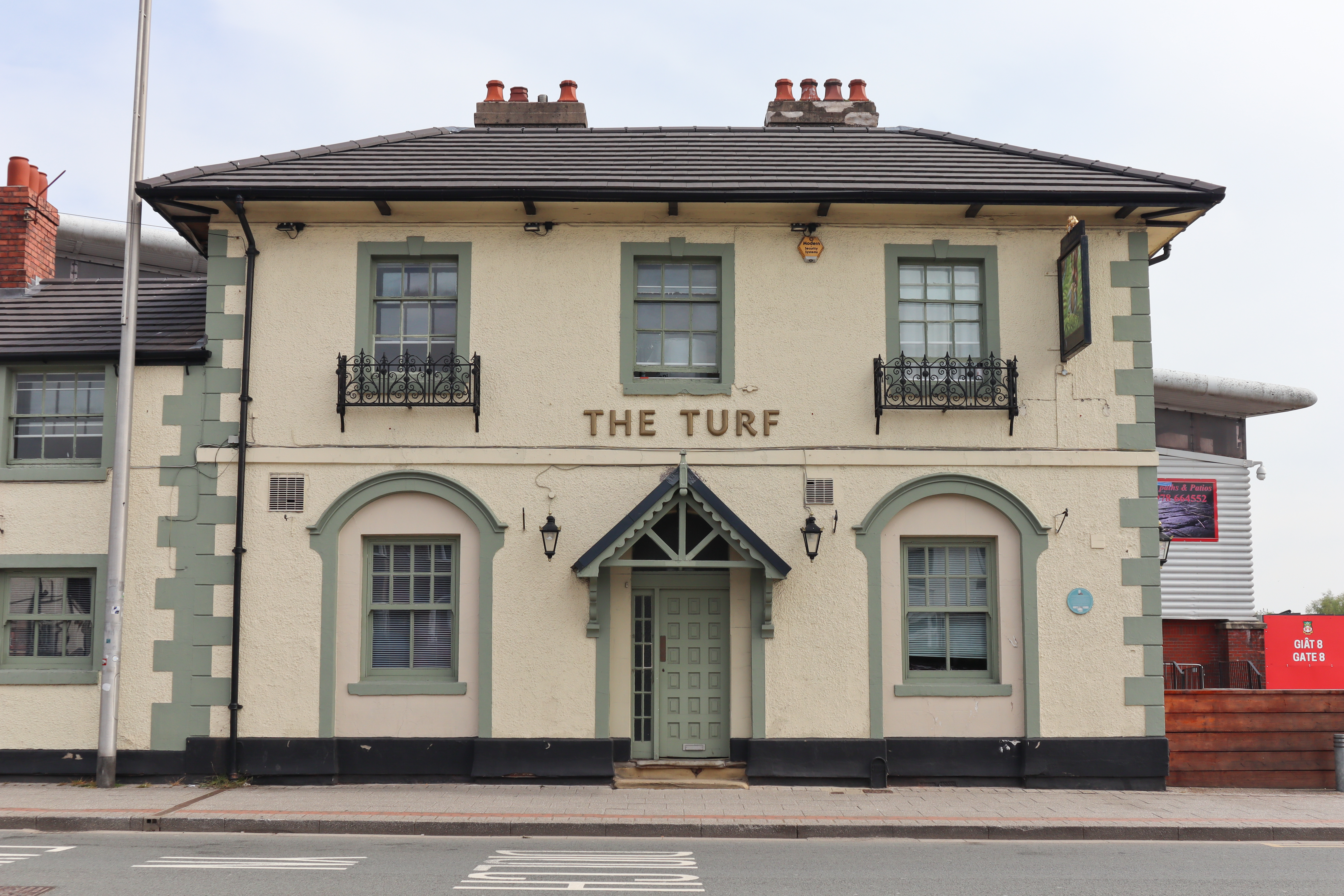 Entrance to a British pub with a sign that reads 'The Turf'.
