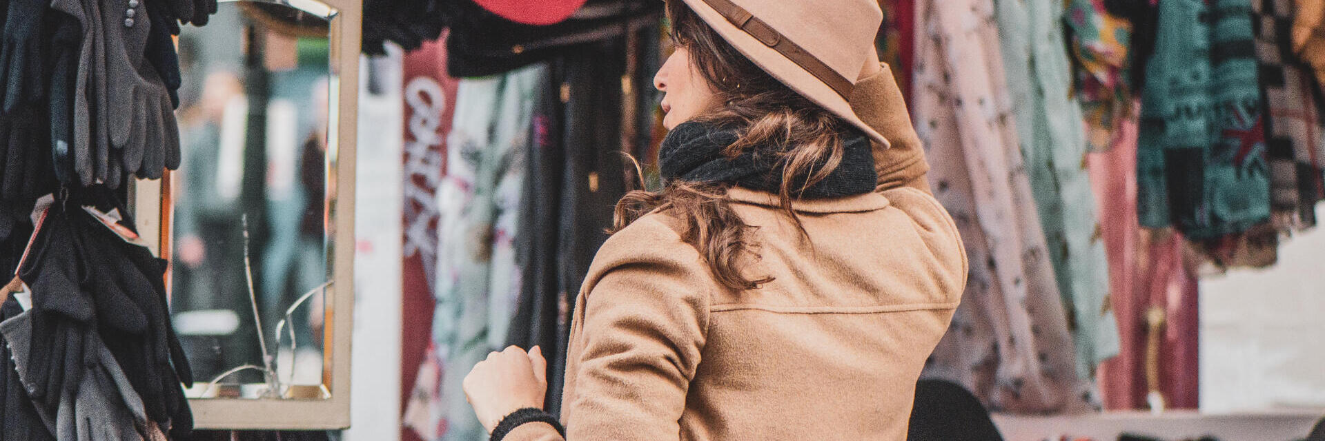 Eine Frau probiert Hüte an einem Stand auf dem Portobello Road Market in London