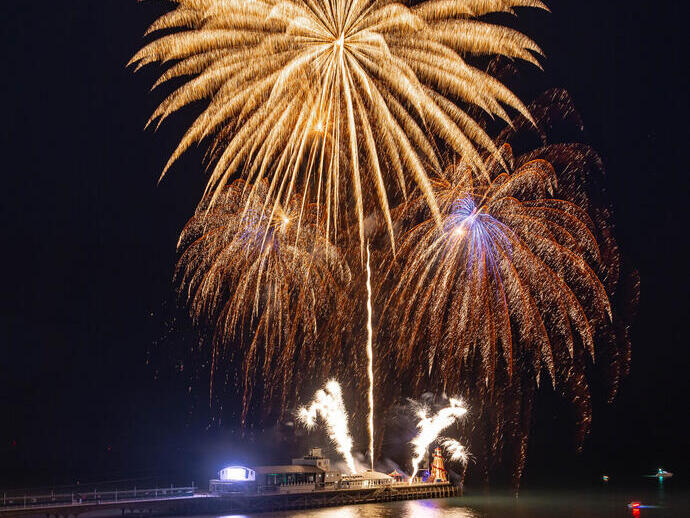 A fireworks display taking place on a seaside pier.
