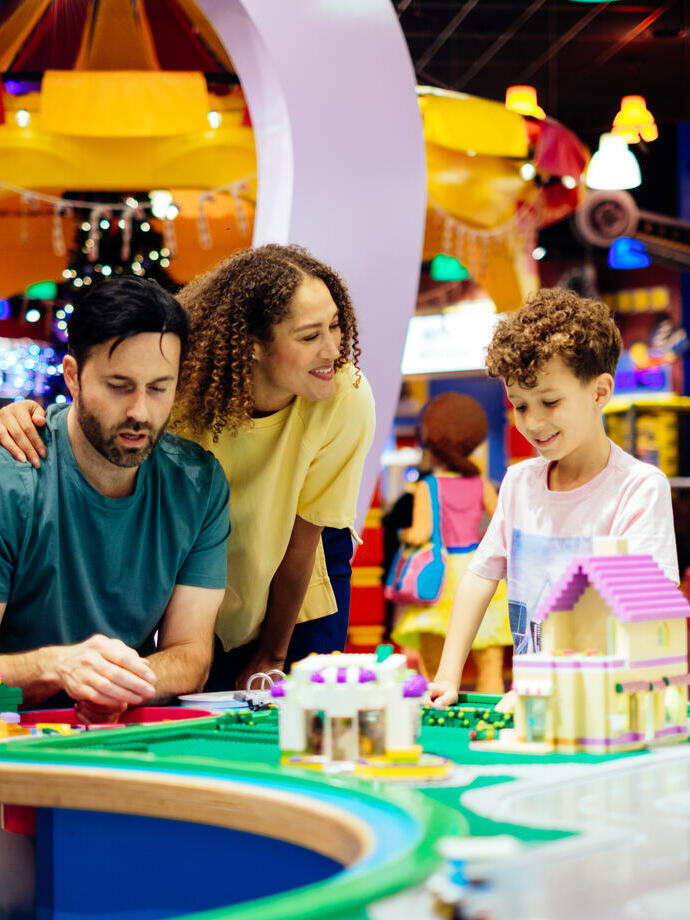 Madre, padre e hijo riendo mientras juegan con Lego
