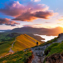 Hiker walking along a path on a mountain ridge at sunrise