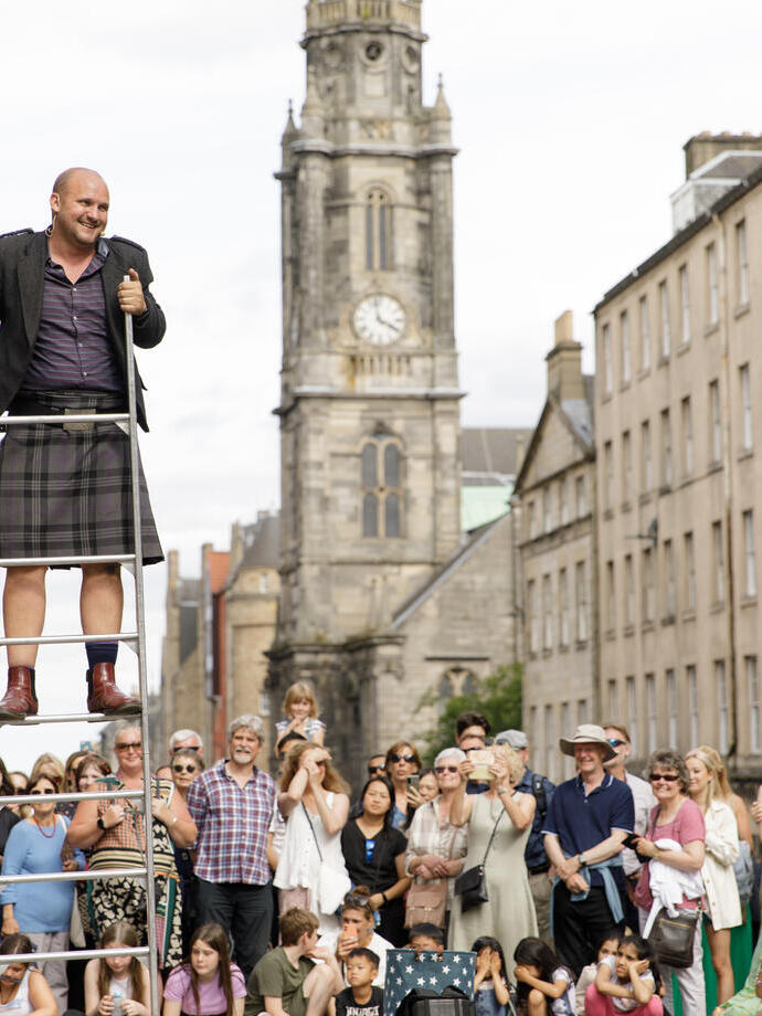Der Straßenkünstler Peter Anderson jongliert während des Festival Fringe 2022 vor einer Menschenmenge auf der Royal Mile in Edinburgh mit Schwertern.