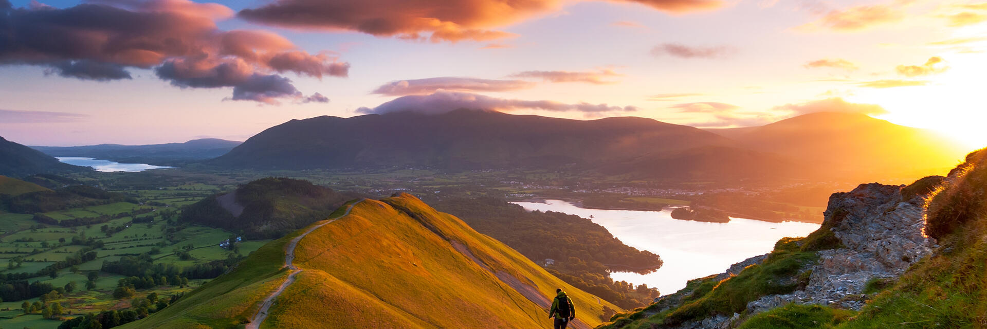 Hiker walking along a path on a mountain ridge at sunrise
