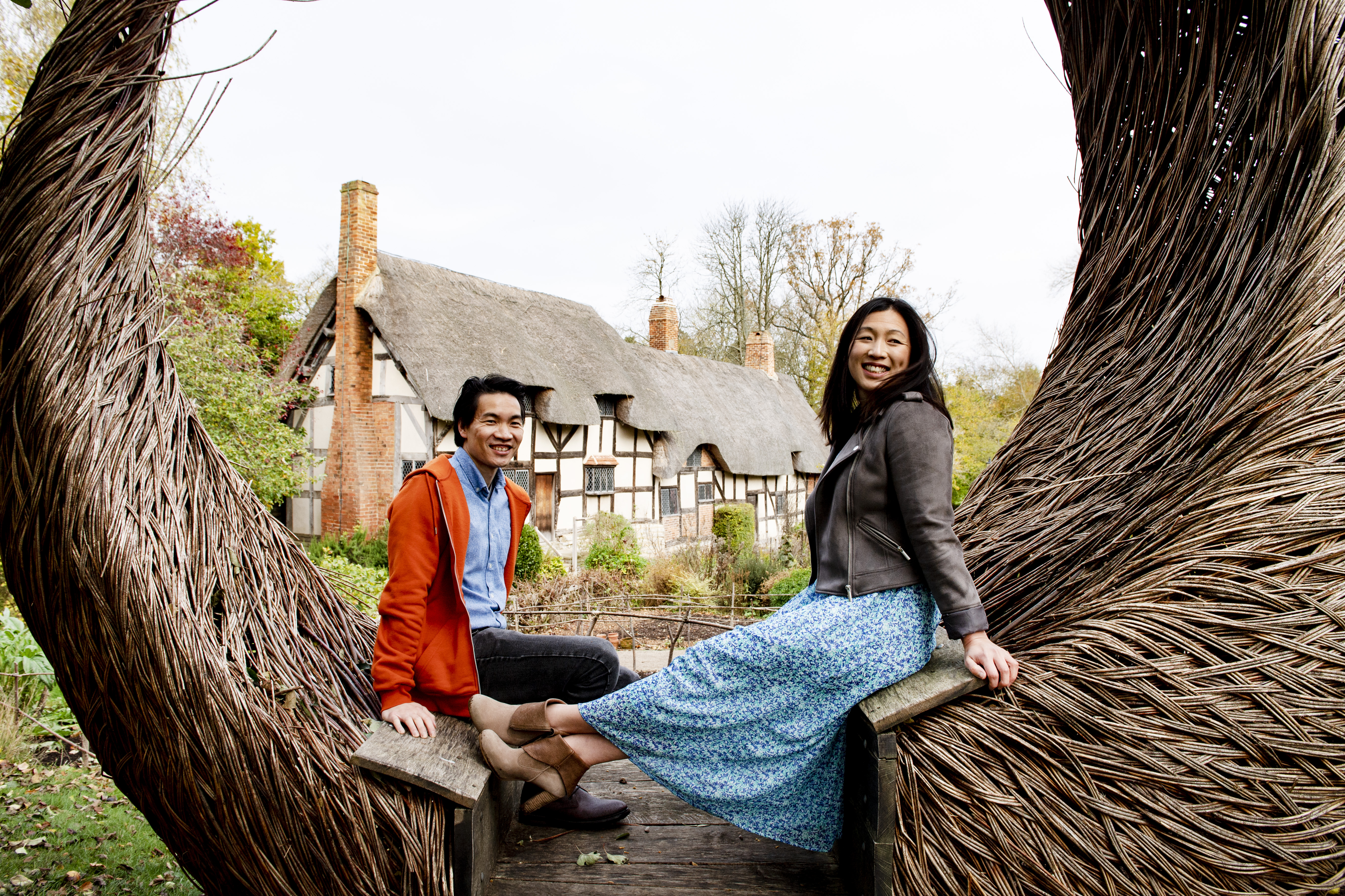 A young couple at Anne Hathaway's Cottage sitting on Tom Hare's 'The Moon Seat', Stratford-upon-Avon, Warwickshire, England