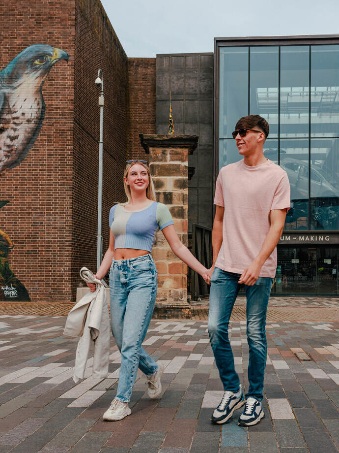 A couple walking past street art outside a museum