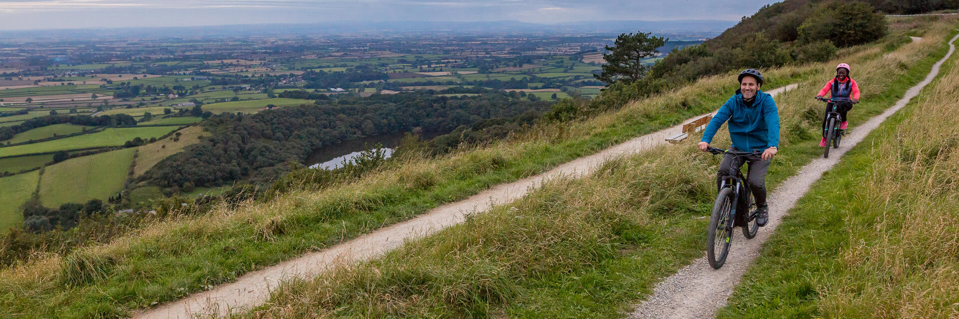 Man and woman riding bikes along a path on a ridge