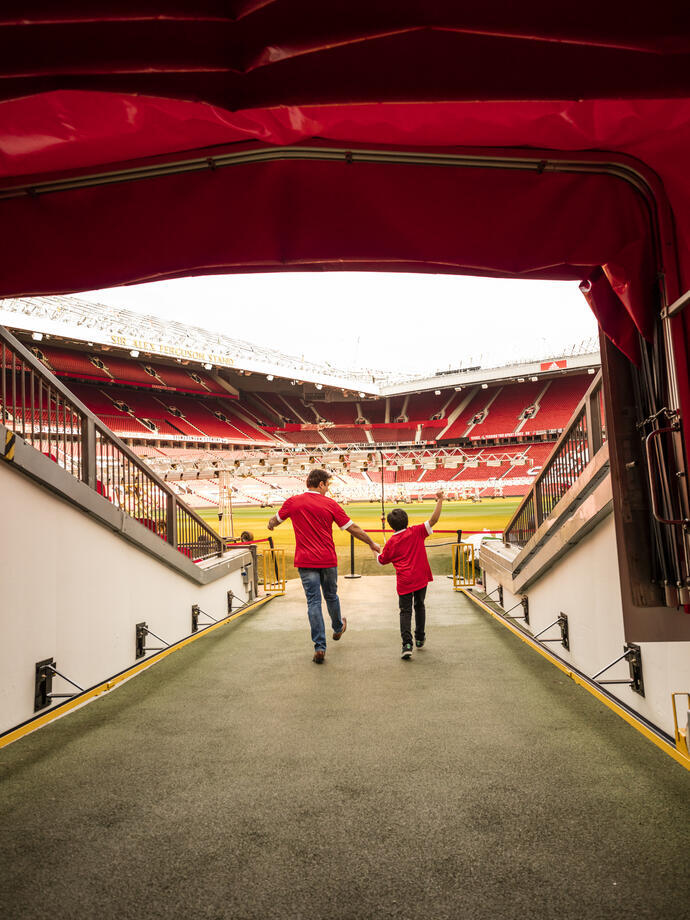 A man and boy in stadium tunnel looking out to pitch