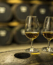 Dos vasos de whisky sobre un barril de roble