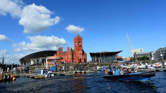 People on a boat leaving a bay with a large red church