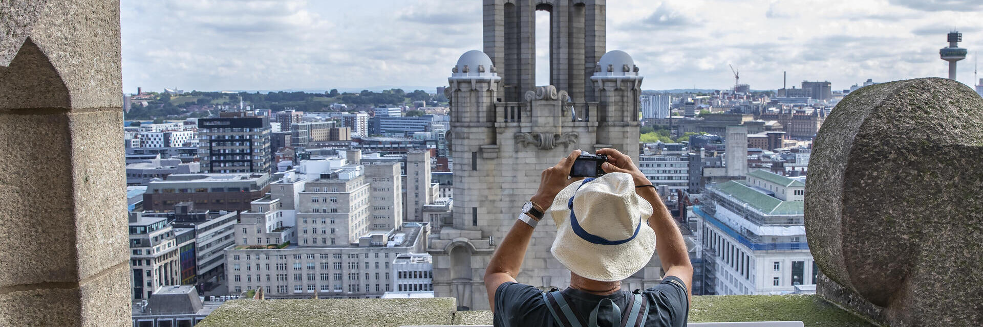 Man photographing a tower in the skyline from a rooftop viewing platform