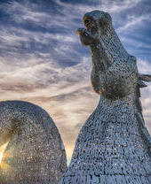 Pair of enormous horse head sculptures at sunset.