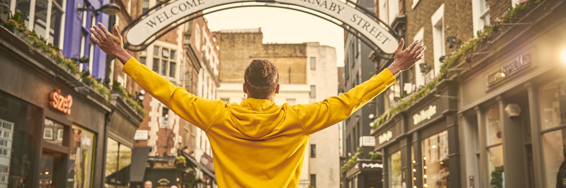 Man standing with arms outstretched on a street