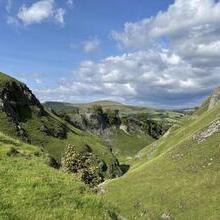 Viewing point from the end of a valley, looking down below with grass in the foreground.