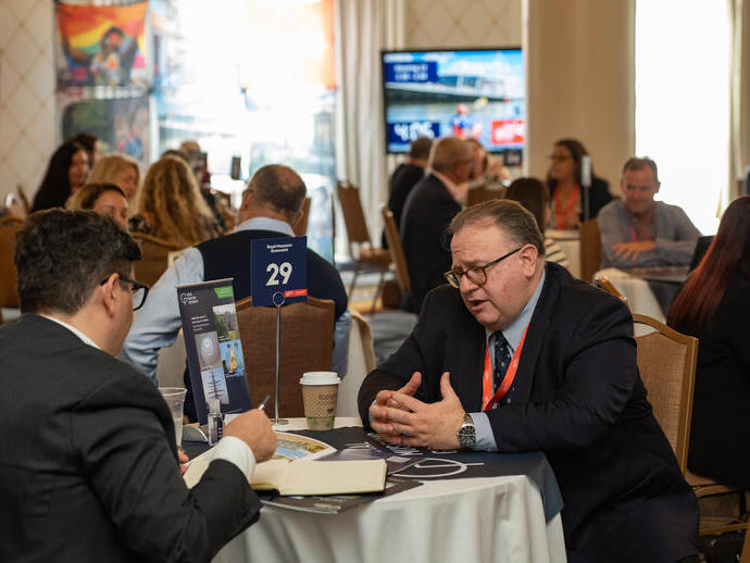 Attendees of an event sit at a table and talk
