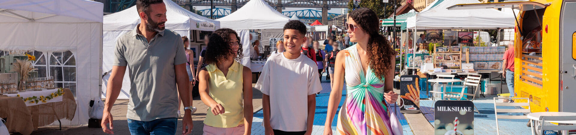 Family walking through stalls at a market in a city