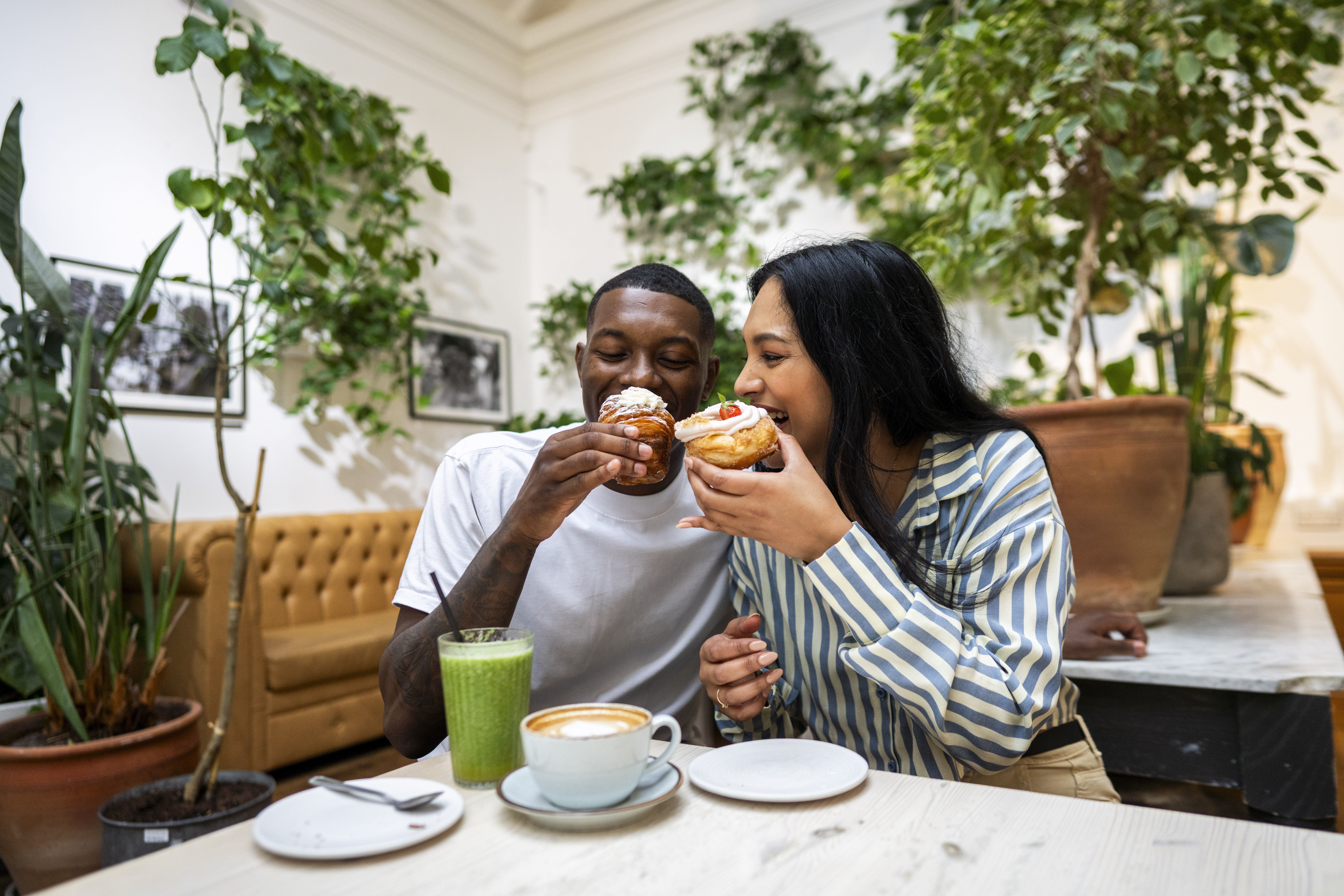 A man and a woman have cake and drinks in a cafe