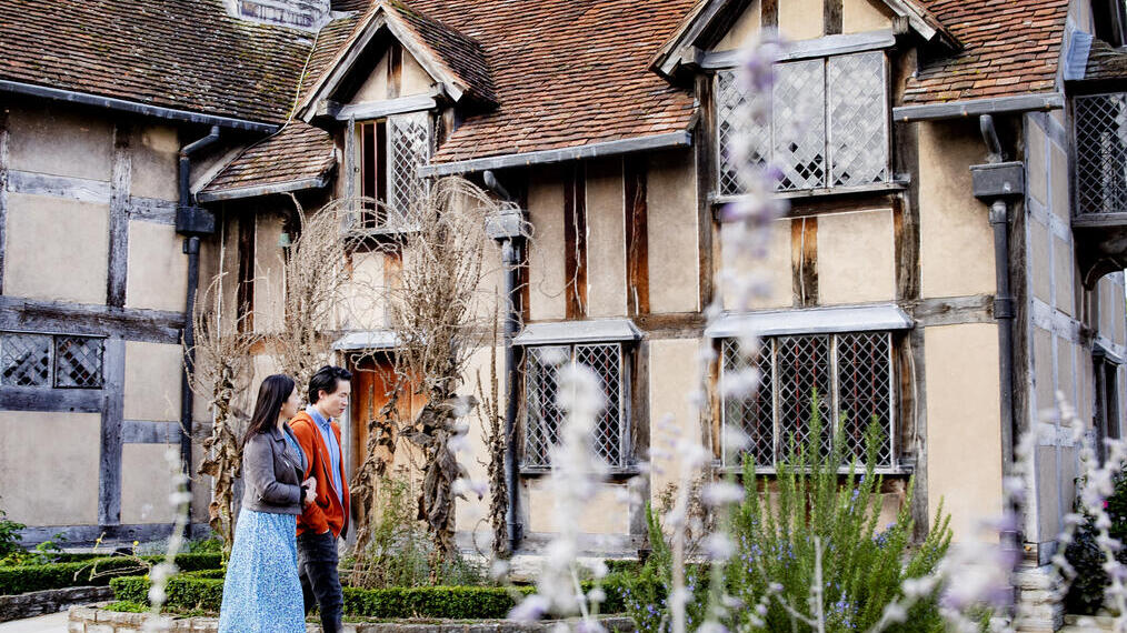 Uomo e donna che camminano fuori da una casa in stile Tudor