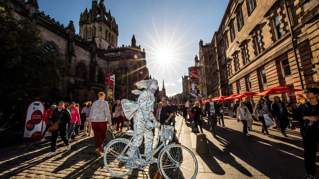 Uomo vestito d'argento in bicicletta che attira la folla