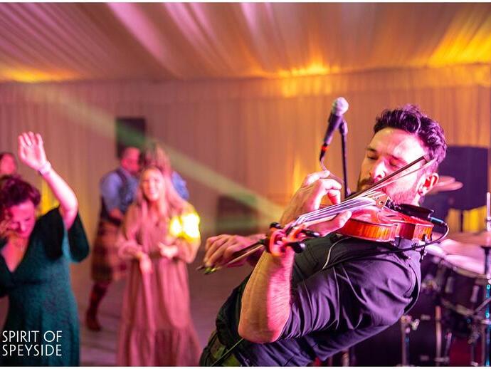 A performer on stage with a violin at the Spirit of Speyside Whiskey Festival