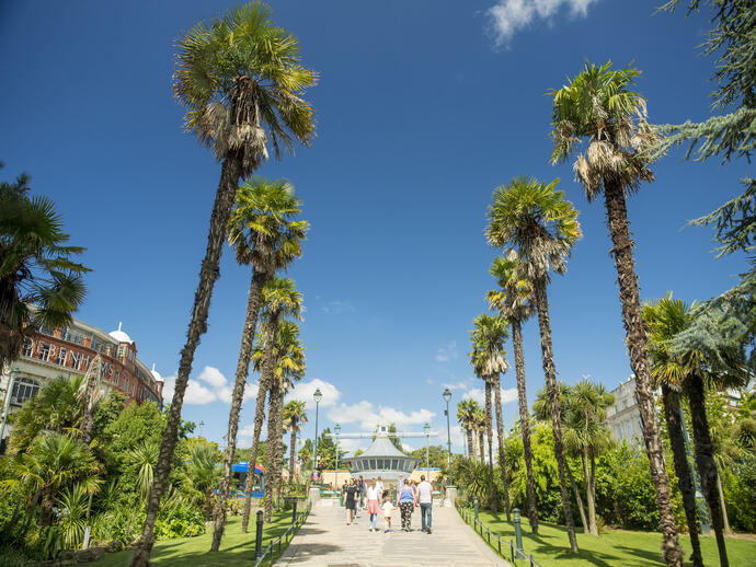 People walking through gardens on a sunny day.
