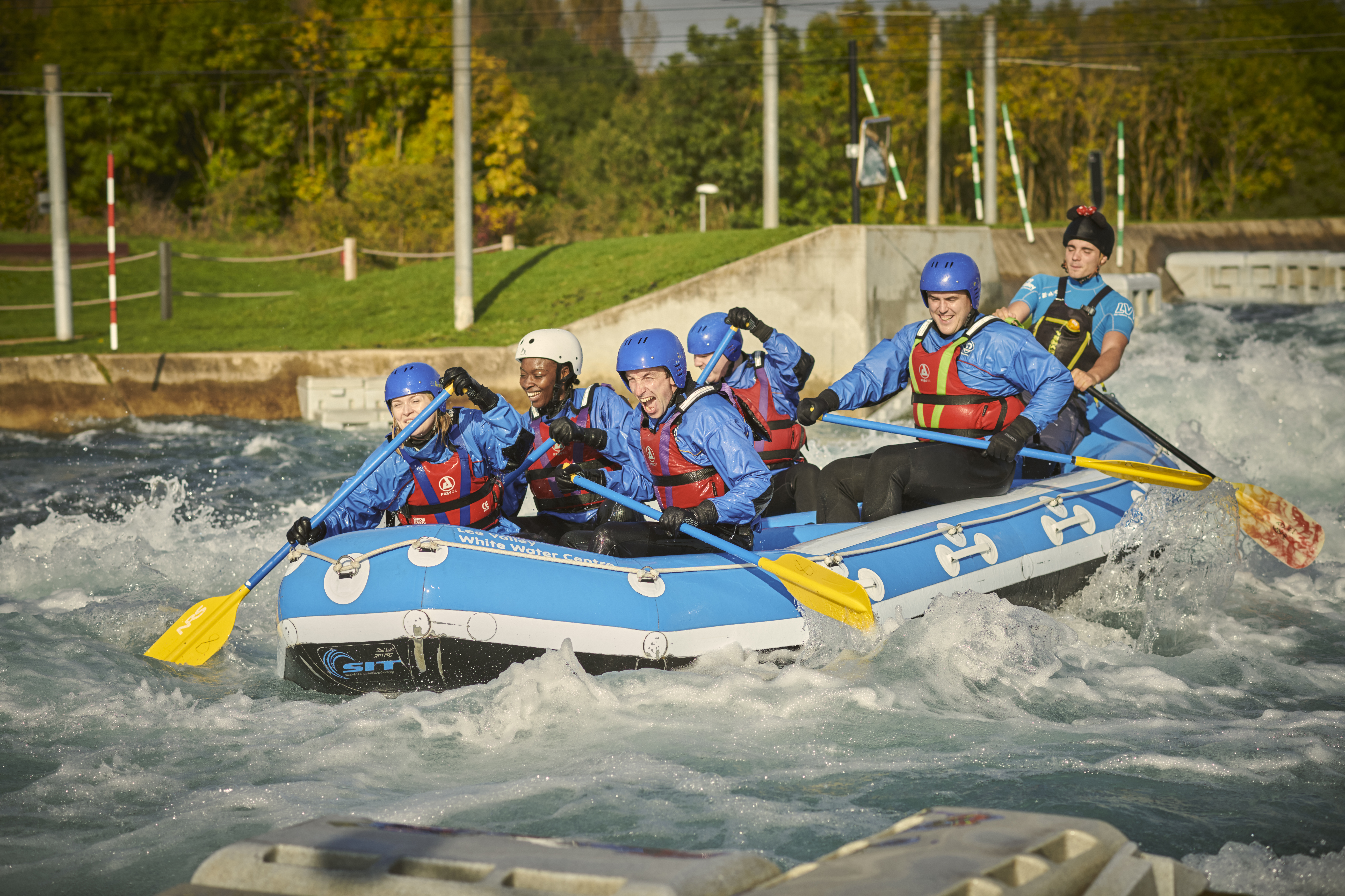 Groupe de personnes dans un rafting avec des pagaies sur une rivière avec des rapides