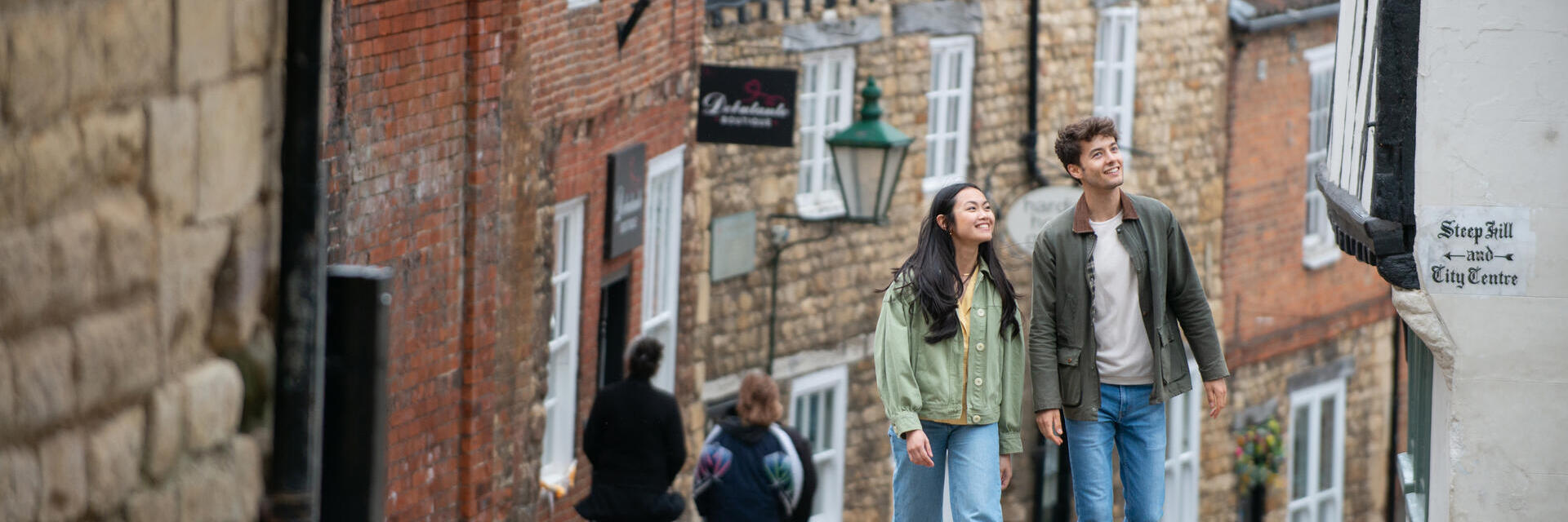 A woman and a man walk up a steep hill in a heritage City