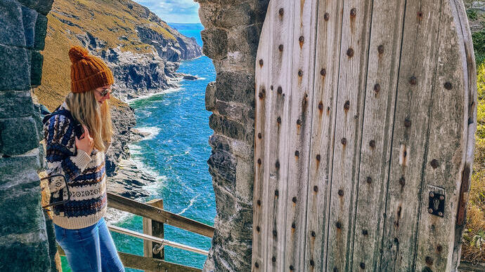 Eine Frau steht auf den obersten Stufen einer Tür mit Blick auf die Küste
