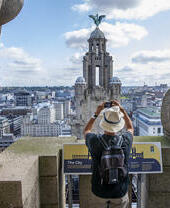 Uomo che fotografa una torre sullo skyline da una piattaforma panoramica sul tetto