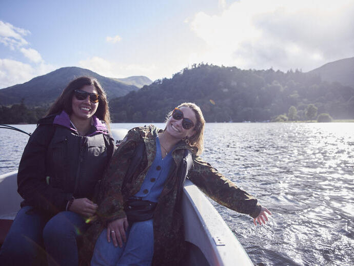 Two women wearing sunglasses on a boat on the lake