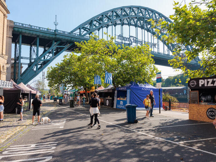 Menschen, die an Marktständen in der Nähe einer Brücke vorbeigehen