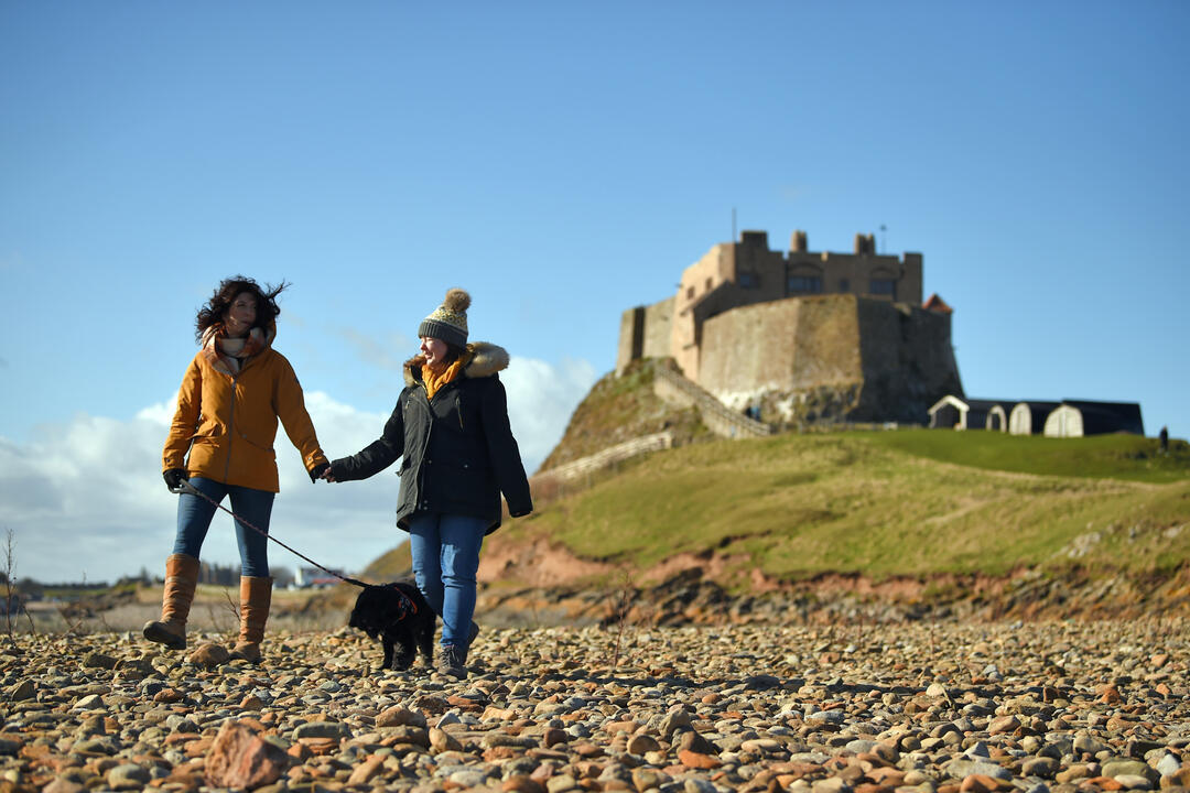 Visitors walking with their dog at Lindisfarne Castle, Northumberland