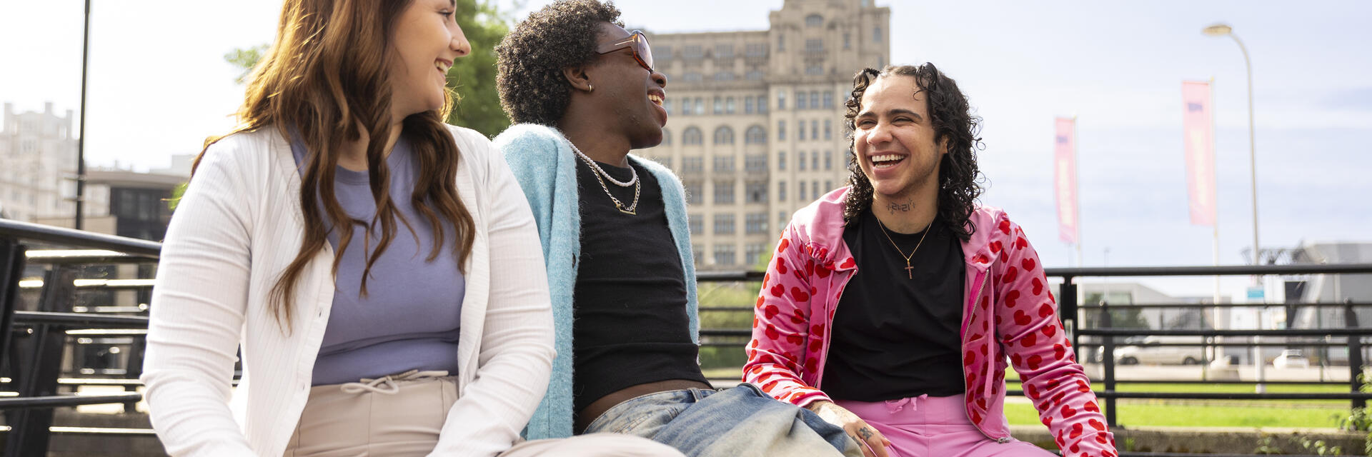 A group of friends sit together on a bench in front of an iconic building