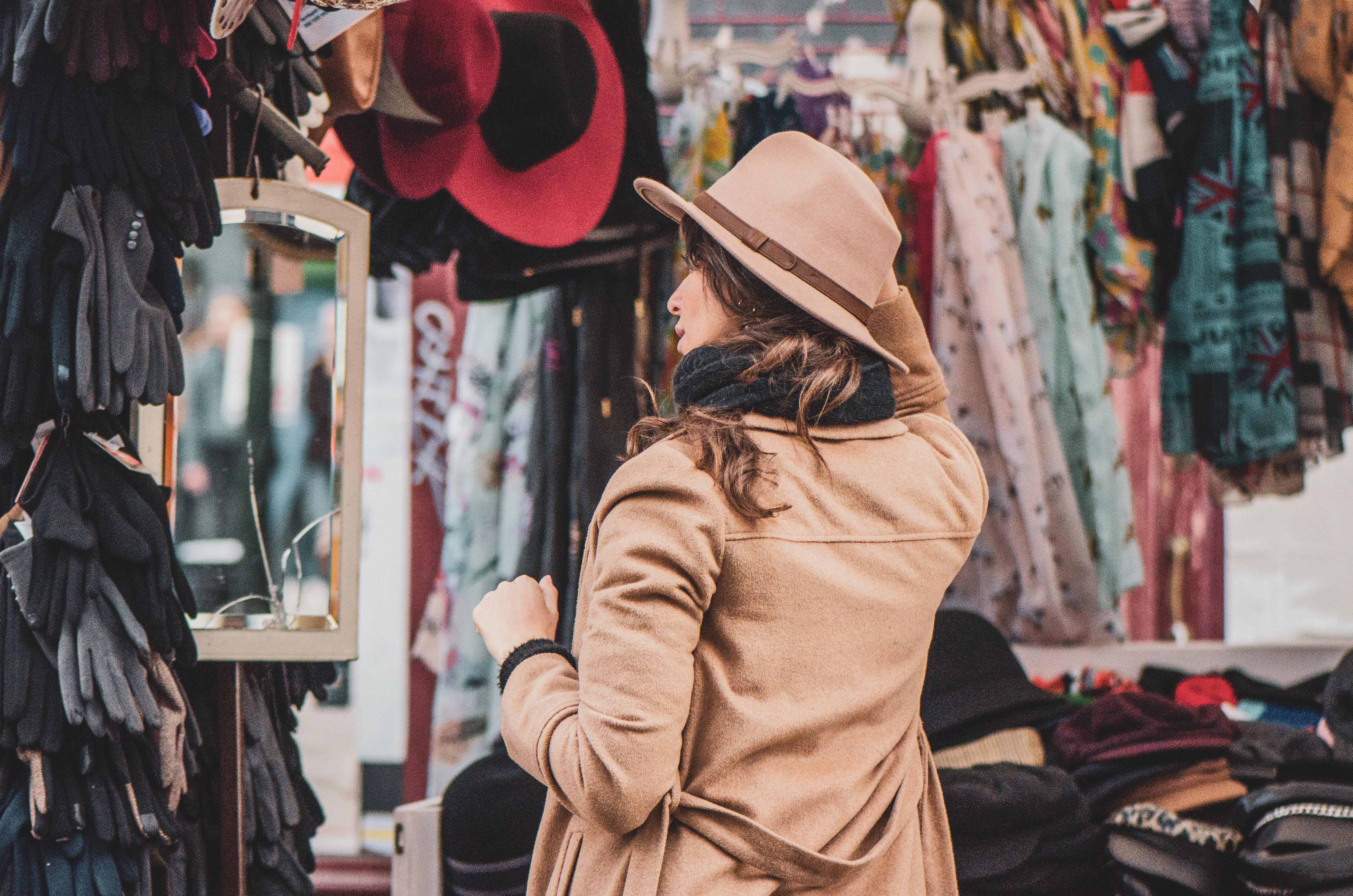 Eine Frau probiert Hüte an einem Stand auf dem Portobello Road Market in London