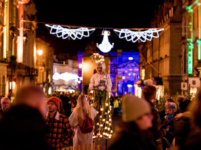 A street entertainer under Christmas lights along the high street in Bath