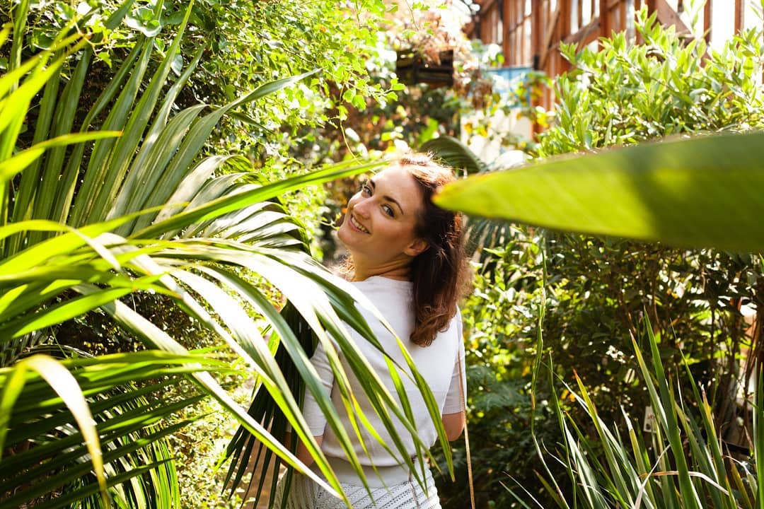 Donna che sorride alla telecamera mentre passeggia nel giardino botanico