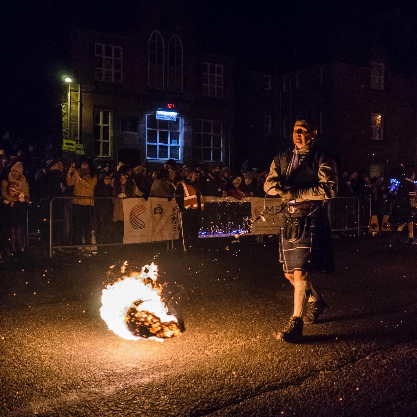 Un homme faisant tournoyer une boule de feu sur un bâton lors d'un défilé à Stonehaven
